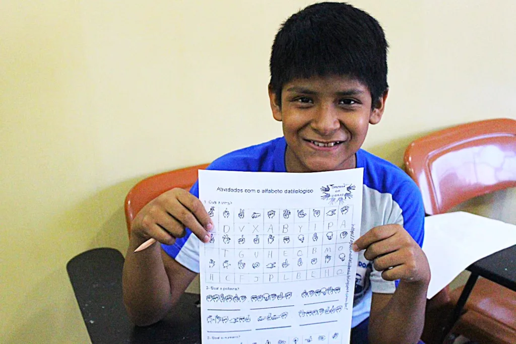 Jovem atendido na Cidade Dom Bosco mostra o vocabulário de sinais na oficina de Libras. Foto: MSMT